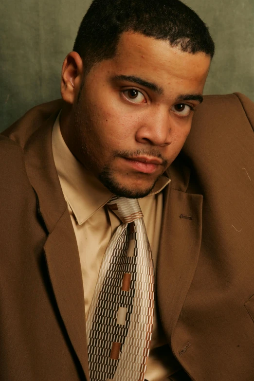 a close up of a person wearing a suit and tie, an album cover, inspired by Gerald Kelly, realism, he is wearing a brown sweater, striking a pose, cinestill!!, mixed race