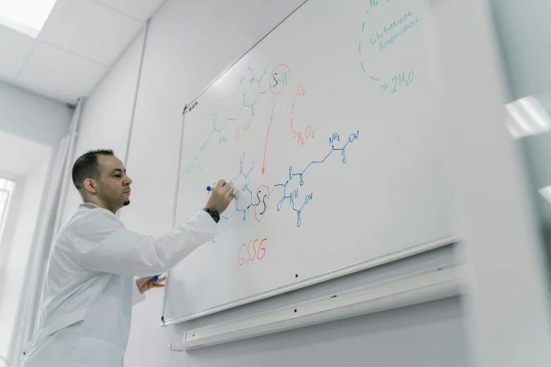 a man in a lab coat writing on a whiteboard, by Adam Marczyński, mohamed chahin style, chemical substances, mid shot, spanish