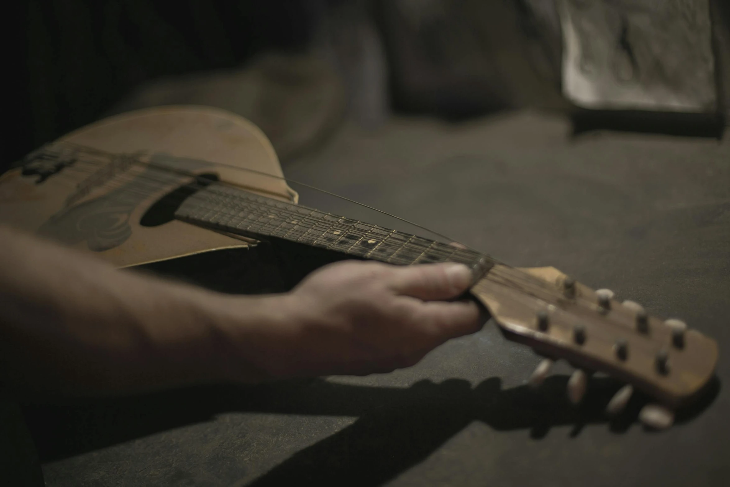 a close up of a person playing a guitar, playing a mandolin, hand on table, during the night