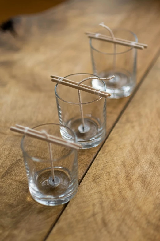 three glasses with chopsticks in them sitting on a table, inspired by Joseph Beuys, purism, copper wire, zen garden, tiny ships docking, handcrafted