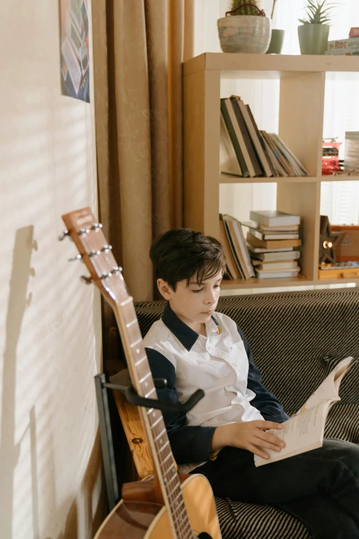 a boy sitting on a couch reading a book, an album cover, by Jang Seung-eop, pexels contest winner, lute, boy's room, profile pic, looking serious