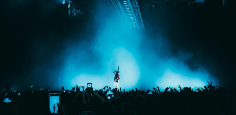 a man standing on top of a stage in front of a crowd, by Sebastian Vrancx, unsplash contest winner, post malone, teal lights, rammstein, 15081959 21121991 01012000 4k