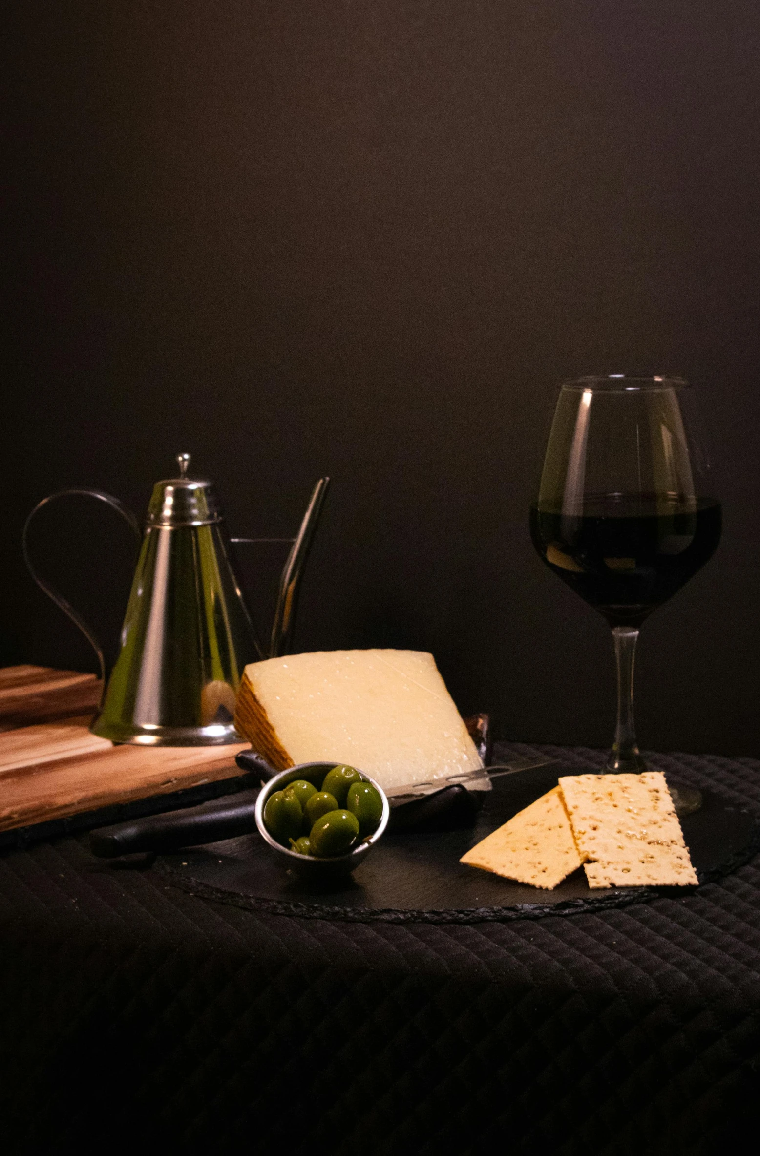 a glass of wine, cheese and olives on a table, by Adriaen Hanneman, pexels contest winner, realism, deep black, black, portrait n - 9, studio shot