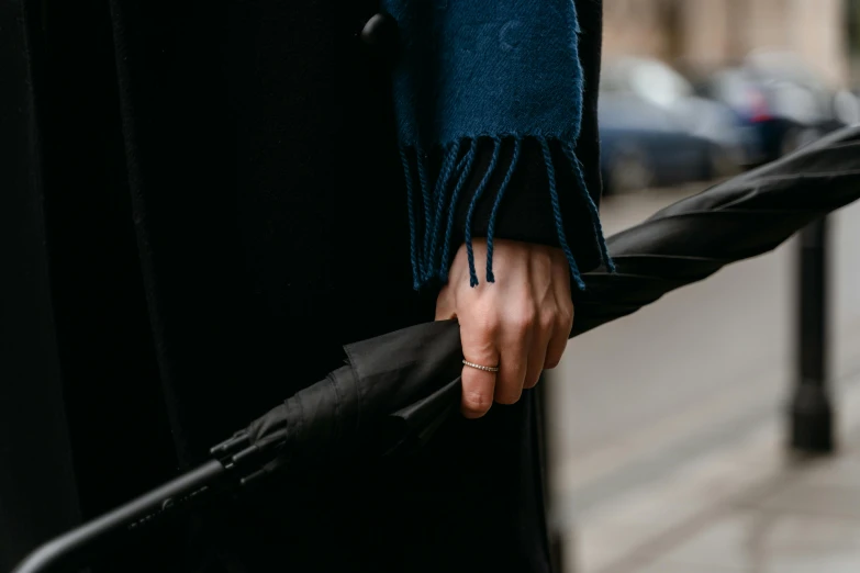 a person holding an umbrella on a city street, trending on pexels, holding jagged scimitar, coat pleats, dark blue and black, sleek hands