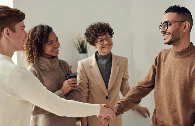 a group of people shaking hands in a room, brown, connection rituals, professional branding, three women