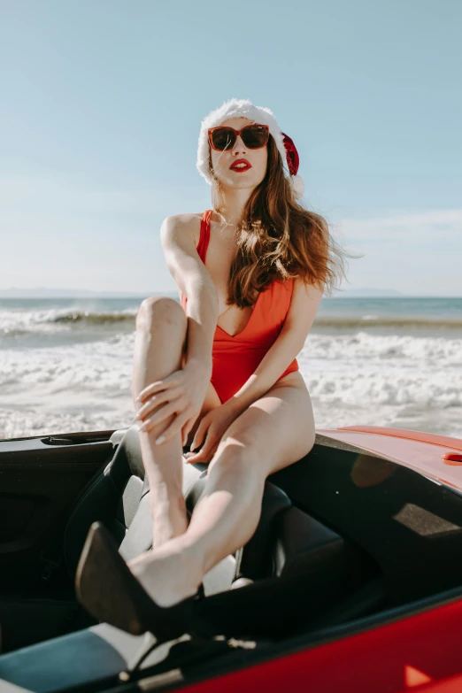 a woman in a santa hat sitting on top of a red car, inspired by Bunny Yeager, trending on pexels, bathing suit, better known as amouranth, gif, boat