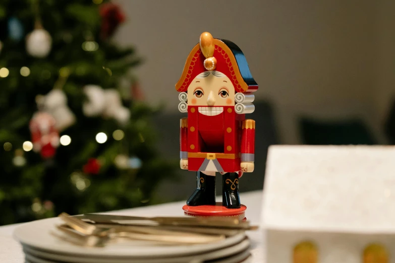 a nutcracker on a table in front of a christmas tree, pexels contest winner, private press, at a dinner table, front facing the camera, multicoloured, wooden decoration