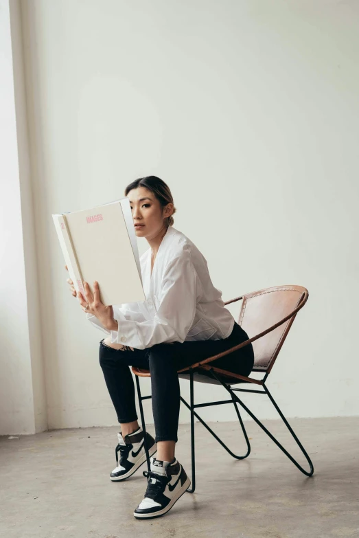 a woman sitting in a chair reading a book, an album cover, inspired by Fei Danxu, pexels contest winner, casual pose, standing, cindy avelino, asher duran