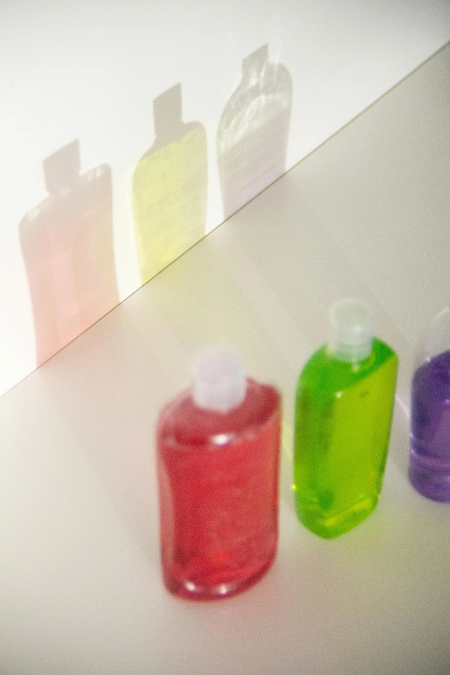 a row of soap bottles sitting on top of a counter, a picture, by Jan Rustem, conceptual art, translucent neon skin, hair gel combed backwards, detailed product image, multicolor