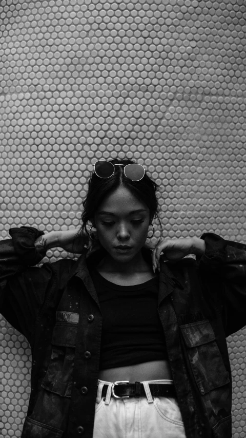 a black and white photo of a woman leaning against a wall, a black and white photo, unsplash, realism, resembling a mix of grimes, tessa thompson, biker, mingchen shen