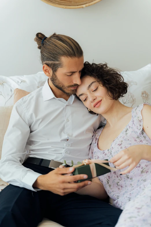 a man and woman sitting on a bed reading a book, a photo, pexels contest winner, romanticism, holding gift, looking her shoulder, gif, lightly dressed