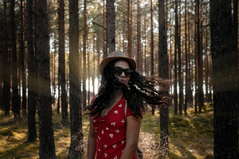 a woman in a red dress standing in a forest, pexels contest winner, wearing sunglasses and a hat, avatar image, long windy hair style, patterned clothing