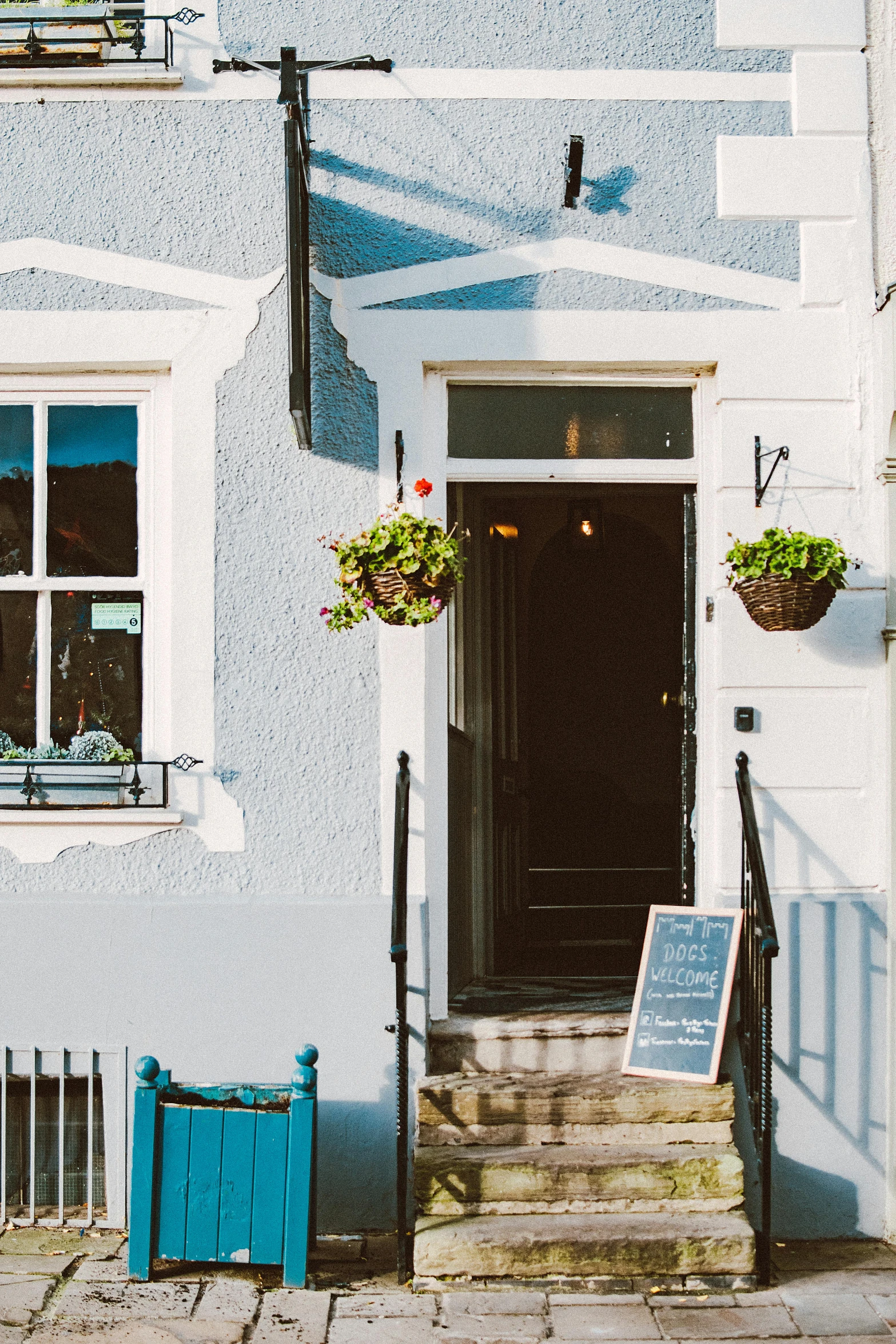 a blue building with a sign in front of it, by Julian Allen, pexels contest winner, private press, restaurant exterior photography, cottage close up, doorway, thumbnail