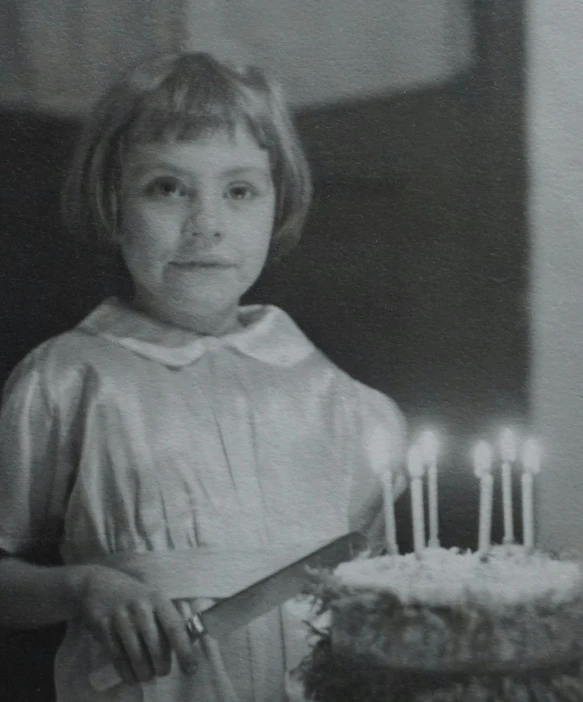 a little girl holding a knife in front of a cake, a black and white photo, in her early 20s, happy birthday candles, video still, ewa juszkiewicz