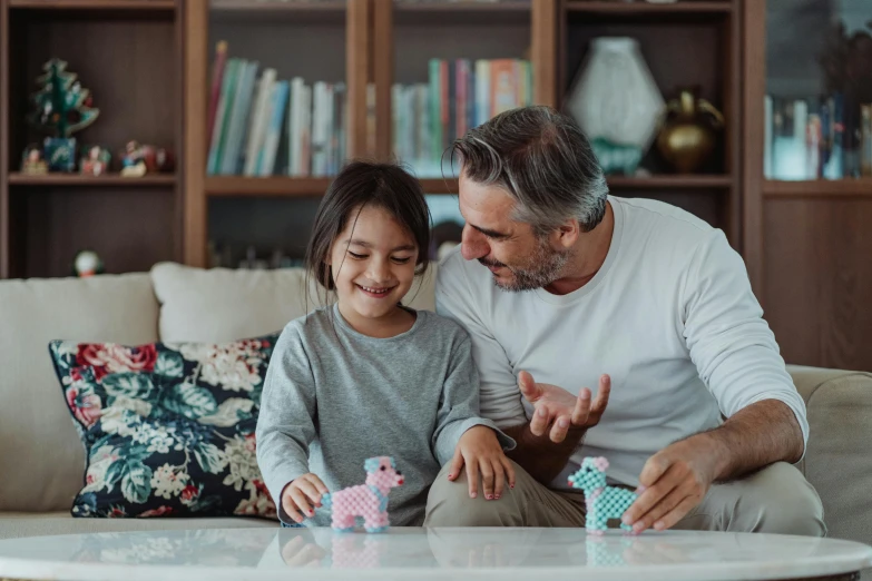 a man and a little girl sitting on a couch, pexels contest winner, board games on a table, avatar image, holding origami qilin, casual playrix games