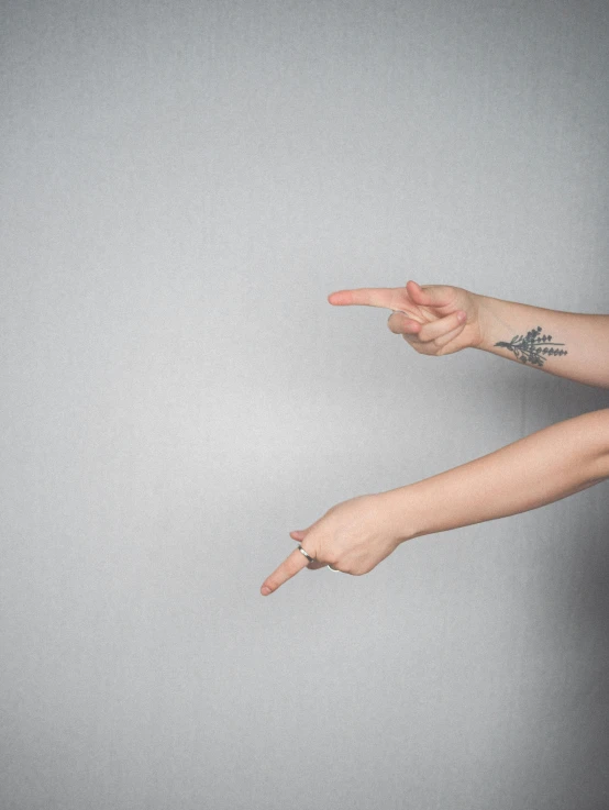 a woman with a tattoo pointing at something, unsplash, grey backdrop, multiple stories, low quality photo, 2000s photo