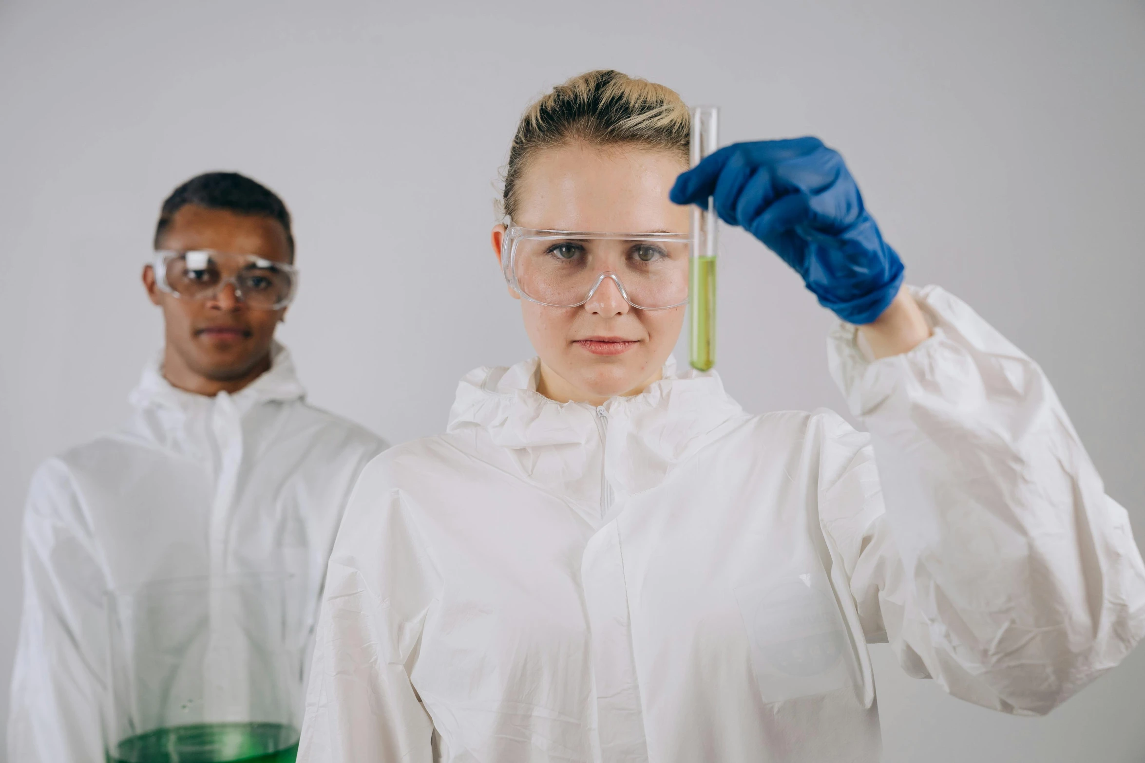 a woman in a lab coat holding a test tube, trending on pexels, portrait of two people, algae, wearing hi vis clothing, avatar image