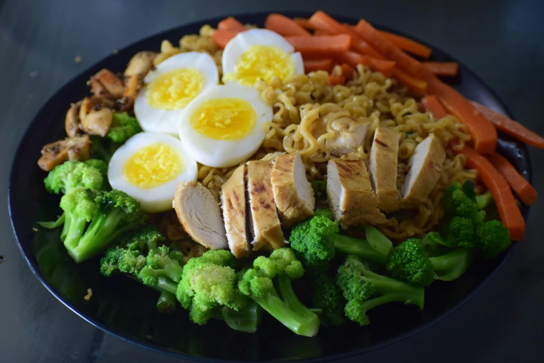 a close up of a plate of food on a table, noodles, veggies, hard boiled, grilled chicken