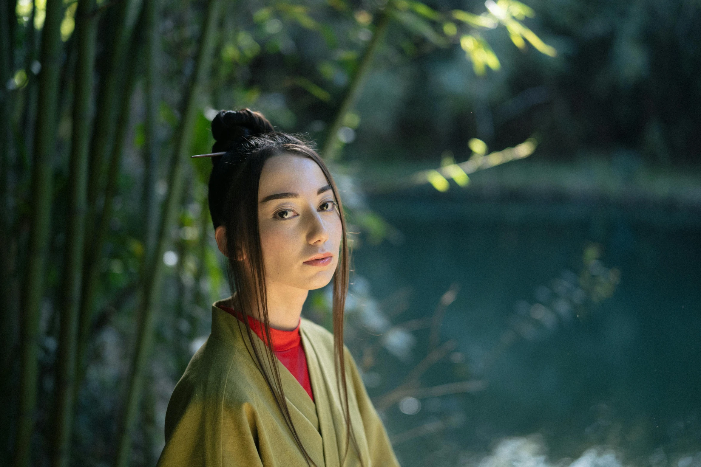 a woman standing in front of a body of water, a portrait, inspired by Gu An, pexels contest winner, shin hanga, green robe, avatar image, bamboo, dilraba dilmurat