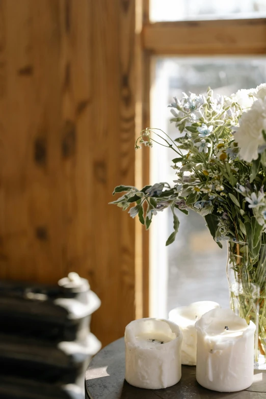 a vase filled with white flowers sitting on top of a table, by Jessie Algie, unsplash, romanticism, sunny bay window, cozy candlelight, herbs, close up shot from the side