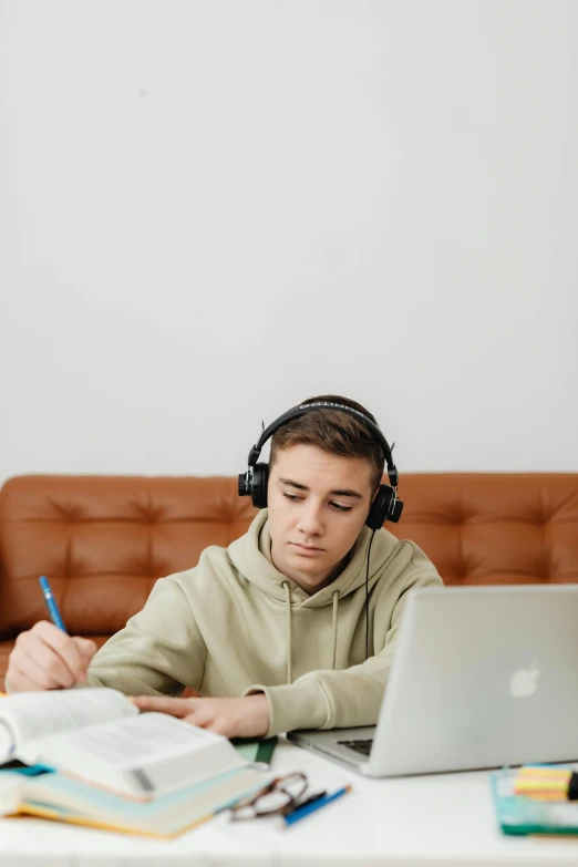 a man sitting at a table with a laptop and headphones, trending on pexels, realism, teen boy, with notes, high quality photo, thumbnail