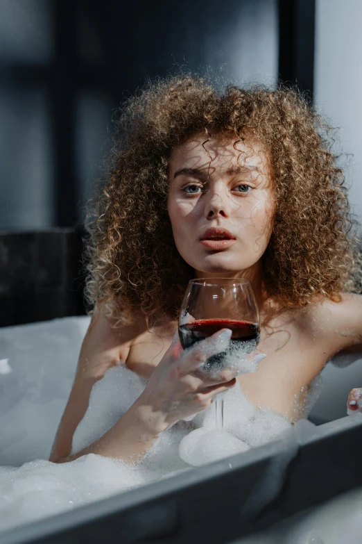 a woman sitting in a bathtub holding a glass of wine, trending on pexels, renaissance, frizzy hair, non binary model, gif, transhumanist hydration