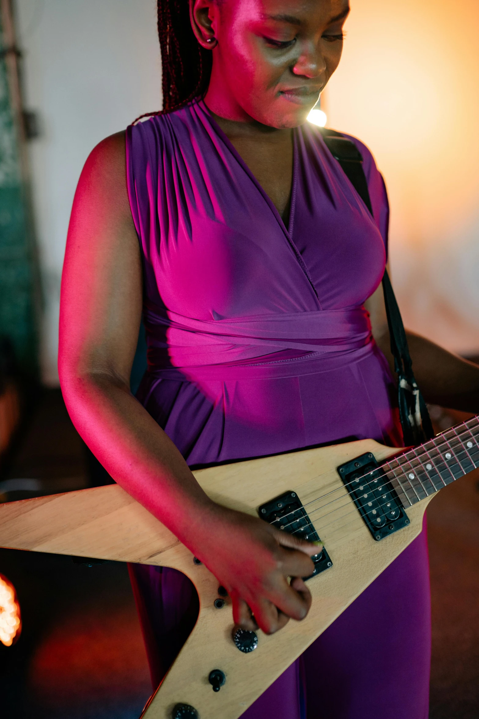 a woman in a purple dress playing a guitar, holding an electric guitar, epk, ( ( dark skin ) ), taken in 2 0 2 0