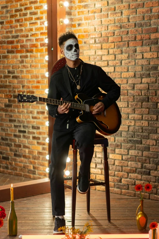 a man sitting on a chair playing a guitar, inspired by Michael Ray Charles, vanitas, skull face paint, promo image, zoomed out full body, black face