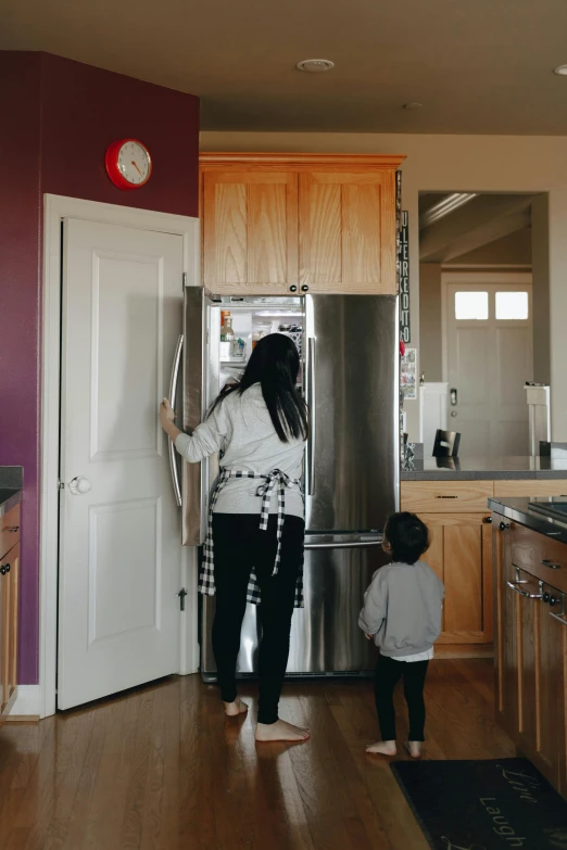 a woman standing next to a child in a kitchen, by Arabella Rankin, pexels contest winner, refrigerator, doors to various bedrooms, half asian, bay area