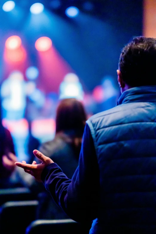 a man standing in front of a crowd of people, pexels, listening to godly music, scene from church, improvisational, backfacing