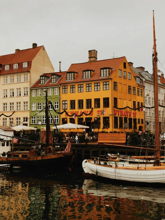 a number of boats in a body of water near buildings, a colorized photo, by Christen Dalsgaard, pexels contest winner, renaissance, vibrant but dreary gold, denmark, to