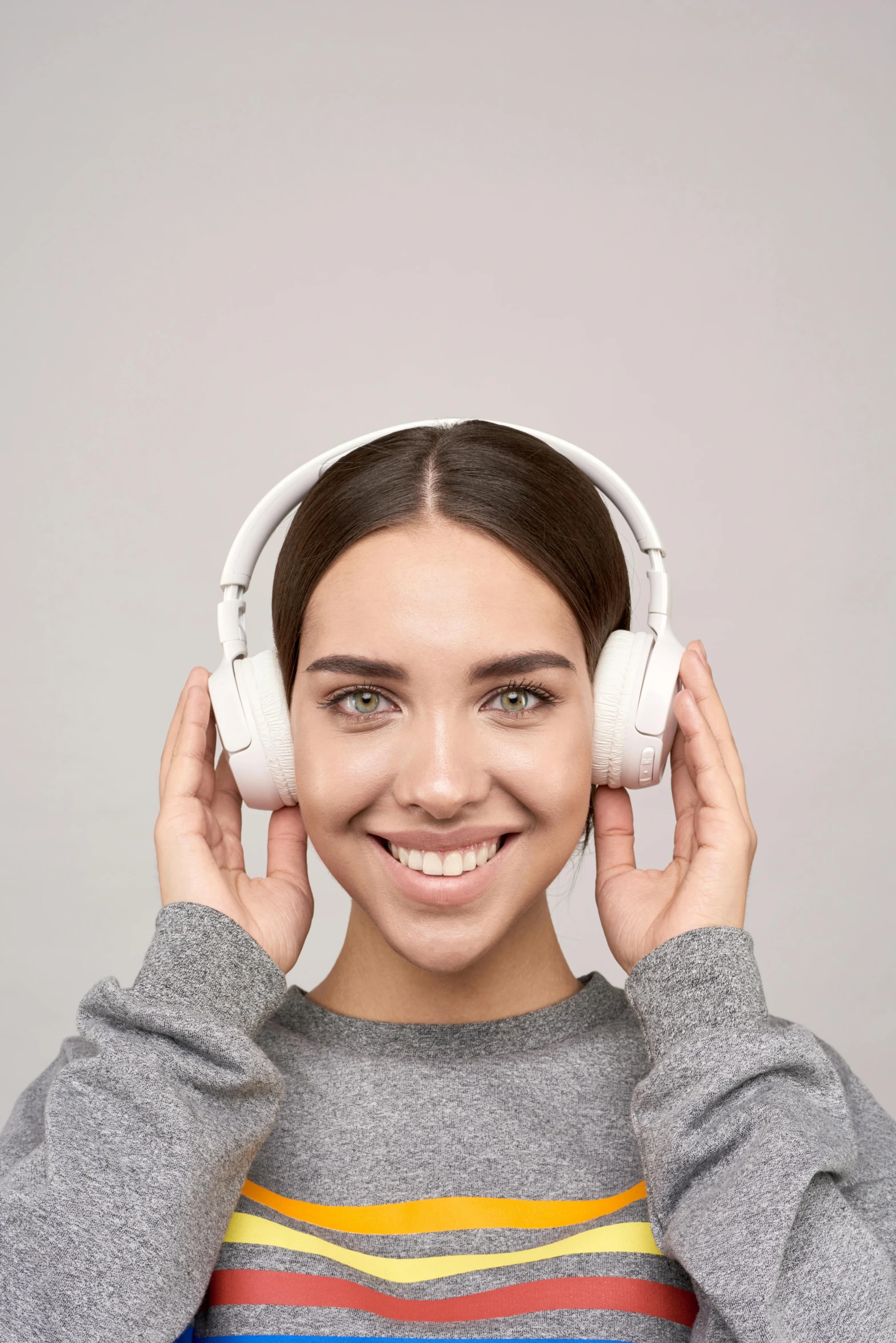 a woman wearing headphones and smiling at the camera, on a gray background, symmetrical features, no - text no - logo, grey ears