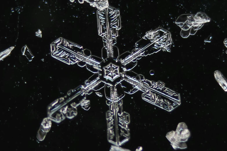 a close up of a snowflake on a black background, a microscopic photo, by Ben Zoeller, pexels, floating crystals, in liquid, credit nasa, video still