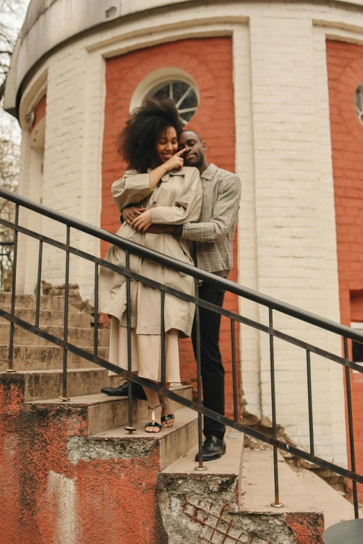 a man and a woman standing in front of a building, pexels contest winner, romanticism, with afro, outdoor staircase, hugging her knees, brown