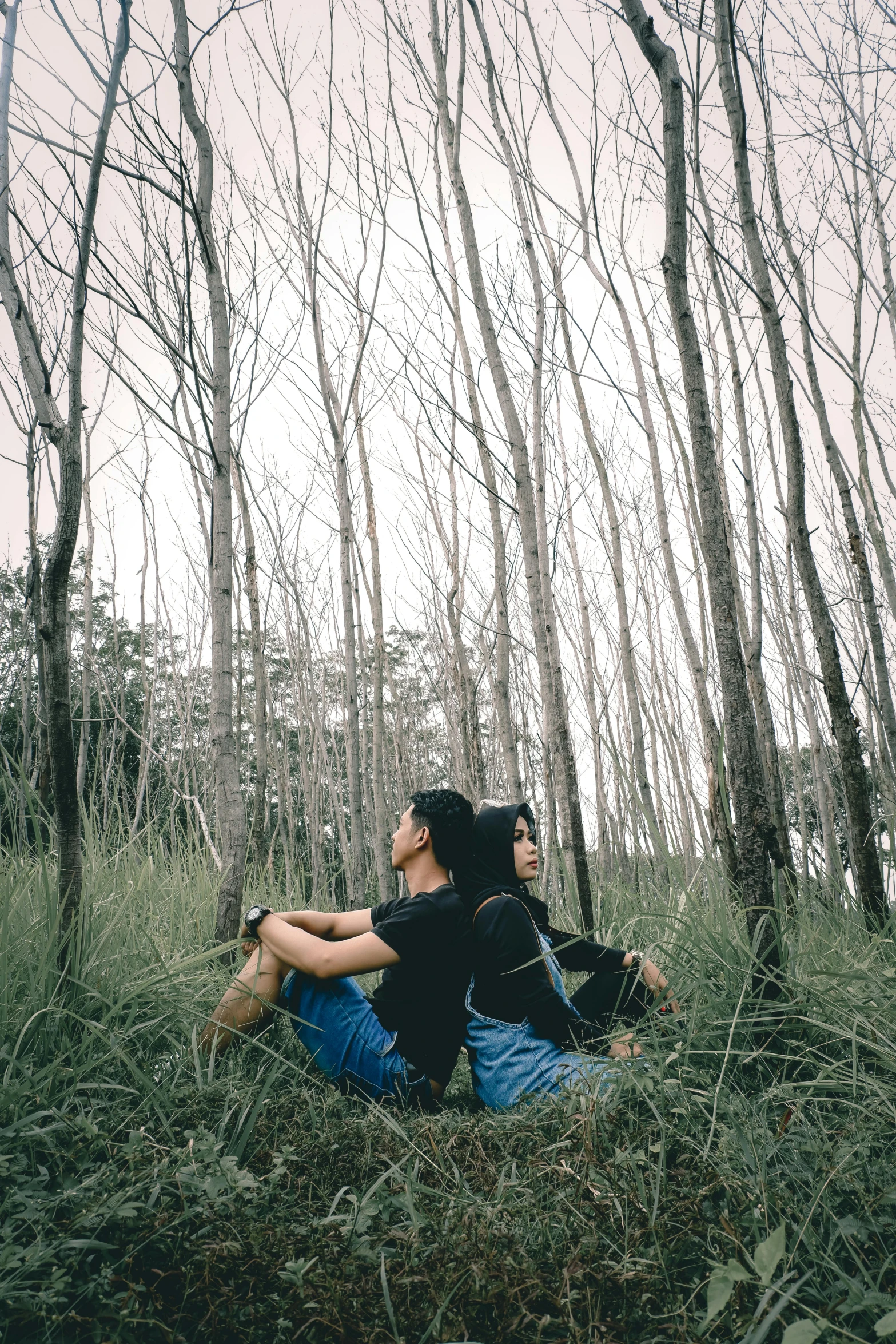 a couple of people that are sitting in the grass, by Basuki Abdullah, pexels contest winner, romanticism, ((trees)), intertwined full body view, ((forest)), 256435456k film