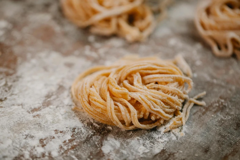 a bunch of pasta sitting on top of a table, by Lee Loughridge, trending on pexels, flour dust, detailed entangled fibres, vanilla, bottom body close up