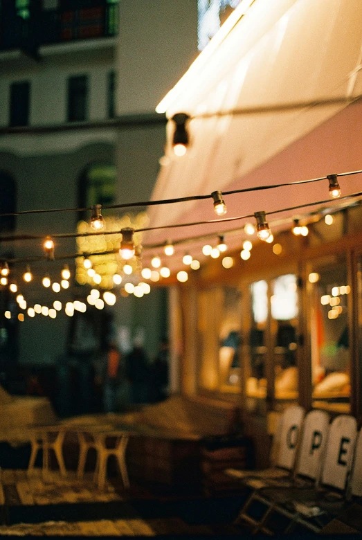 a street filled with lots of tables and chairs, unsplash, some bulb lights, soft outdoor light, quaint, eating outside