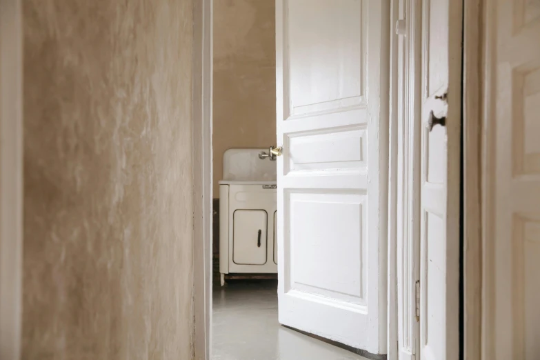 a view of a kitchen through an open door, inspired by Rachel Whiteread, unsplash, minimalism, swedish style, ivory rococo, apartment hallway, taupe