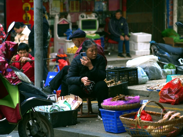 a group of people sitting on the side of a street, inspired by Wang Yi, pexels, belongings strewn about, sichuan, square, an old lady