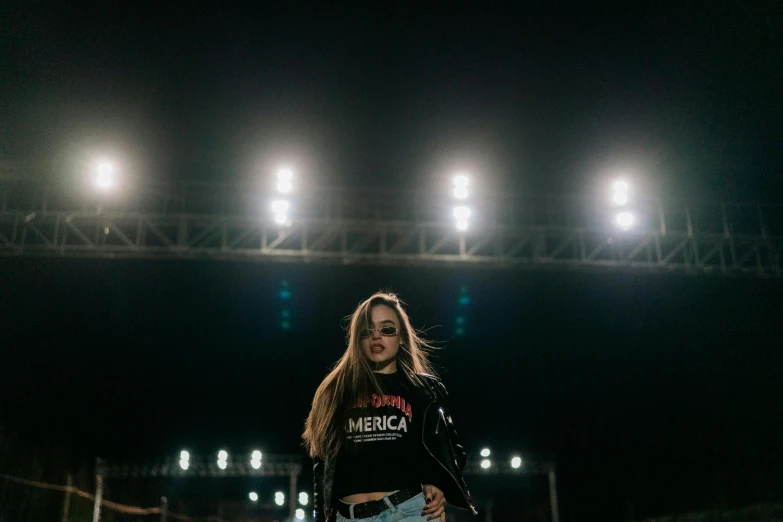 a woman standing on top of a tennis court holding a racquet, inspired by Elsa Bleda, unsplash contest winner, black shirt with red star, fashion show, on a football field, stage lights