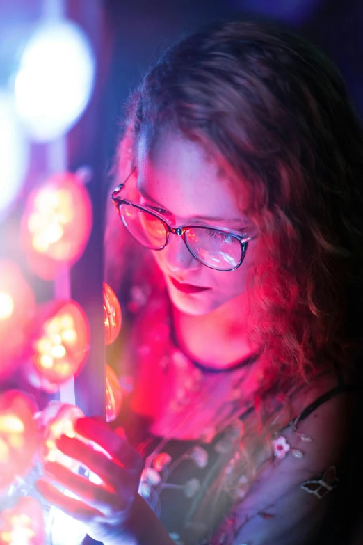 a woman in glasses looking at a cell phone, pexels, process art, red led lights, glowing lamps, covered in circuitry, student