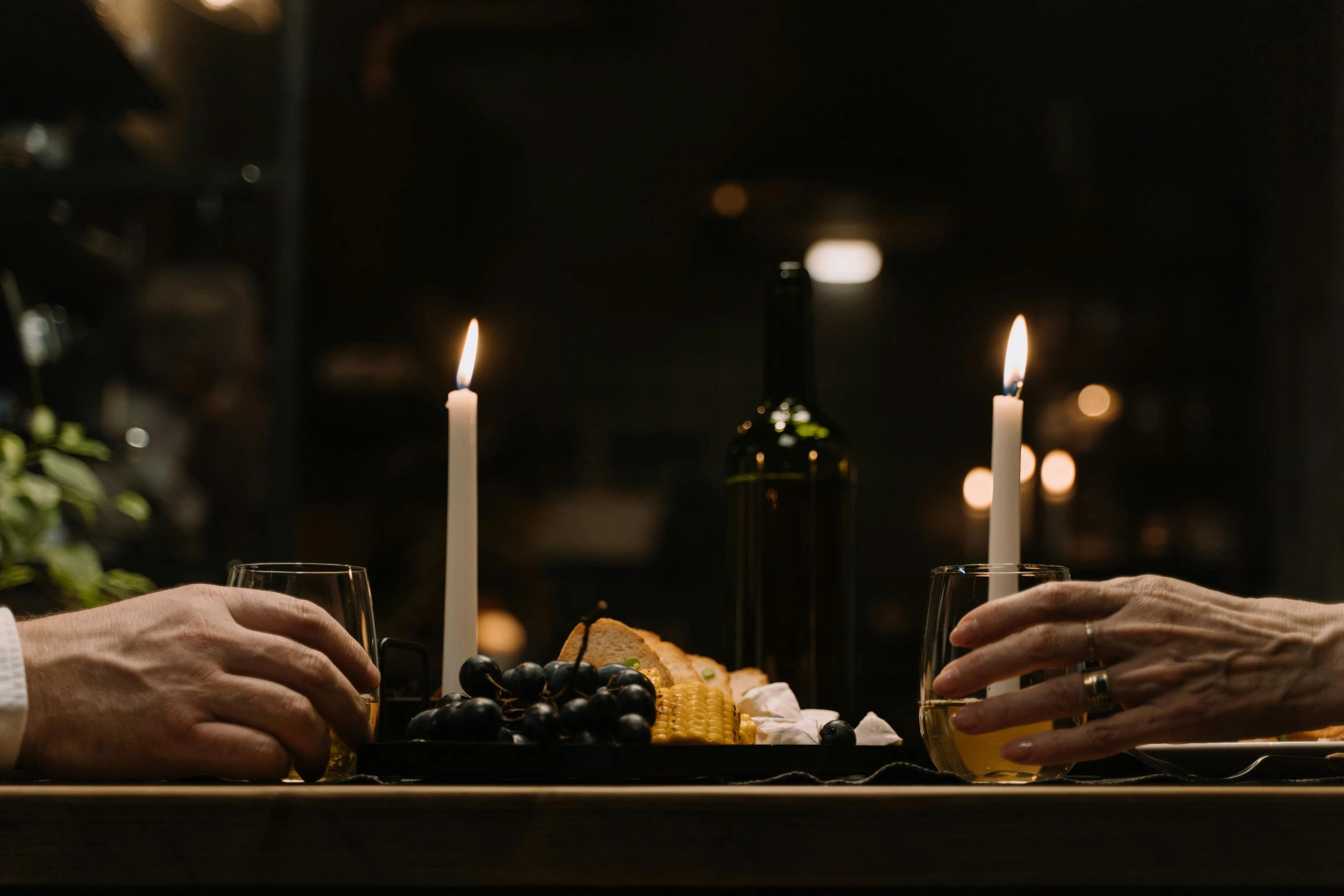 a couple of people that are sitting at a table, pexels contest winner, white candles, with a bottle of wine, it's late at night, waxy candles