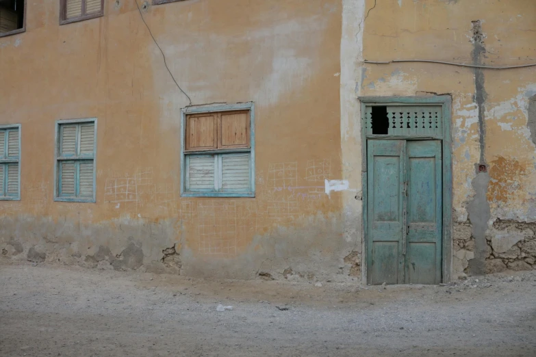 an old building with a green door in front of it, an album cover, pexels contest winner, arte povera, in egypt, light - brown wall, background image, settlement