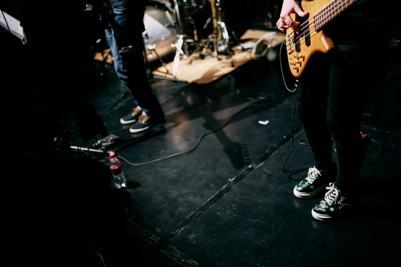 a person standing on a stage with a guitar, pexels contest winner, antipodeans, feet on the ground, bassist, black lips, epk