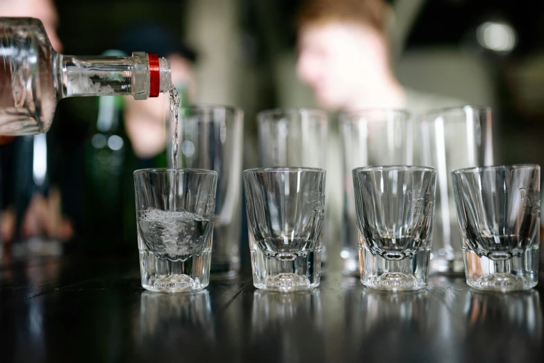 a group of shot glasses sitting on top of a table, pouring, ben watts, multiple stories, crystal clear