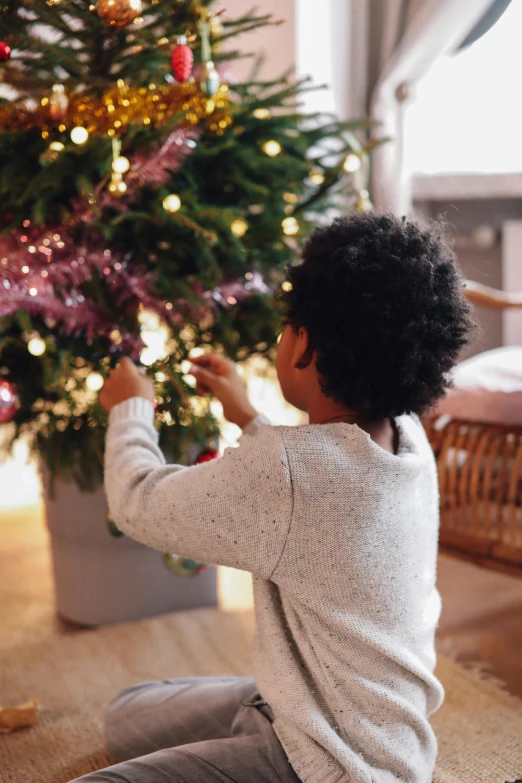 a little boy sitting on the floor in front of a christmas tree, pexels, happening, emitting light ornaments, gif, detail shot, profile image