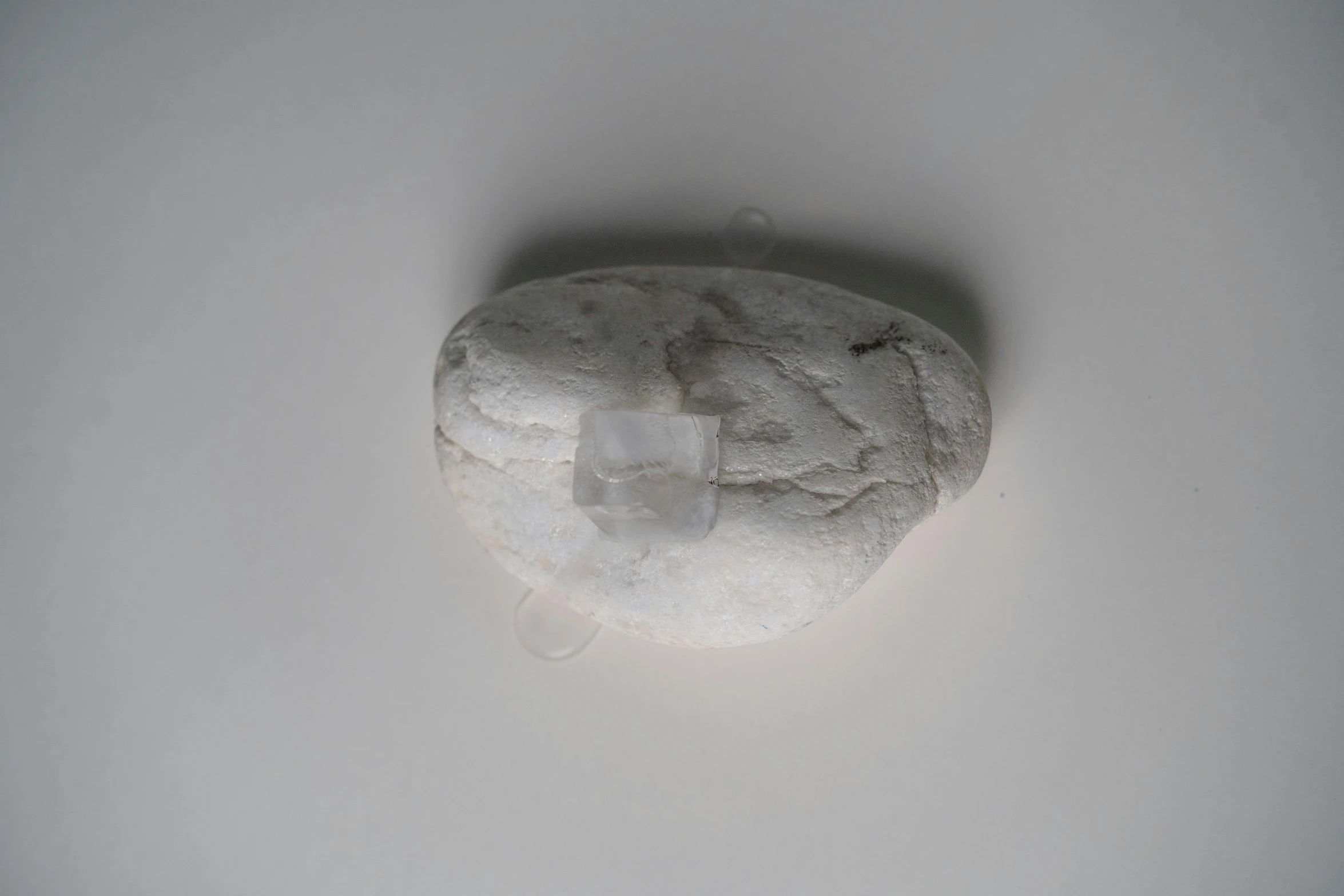 a close up of a rock on a white surface, inspired by Rachel Whiteread, figuration libre, isolate translucent, amulet, centred, bread