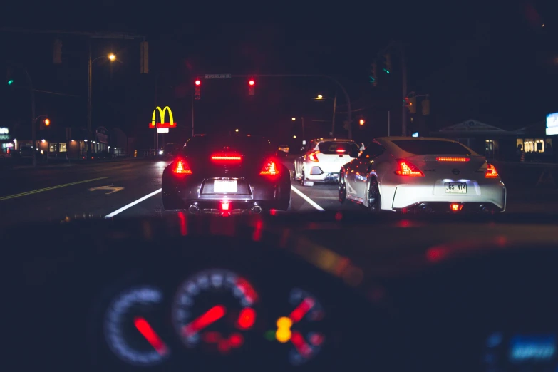 a number of cars on a city street at night, unsplash, realism, mcdonald, speeder, inside of a car, pov photo