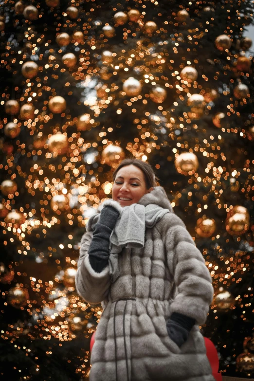 a woman standing in front of a christmas tree, by Julia Pishtar, pexels contest winner, wearing a luxury fur coat, in moscow centre, 15081959 21121991 01012000 4k, golden glistening