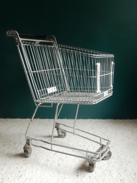 a shopping cart sitting in front of a green wall, by Bernard D’Andrea, hyperrealism, 7 0 - s, highly polished, rare, grey